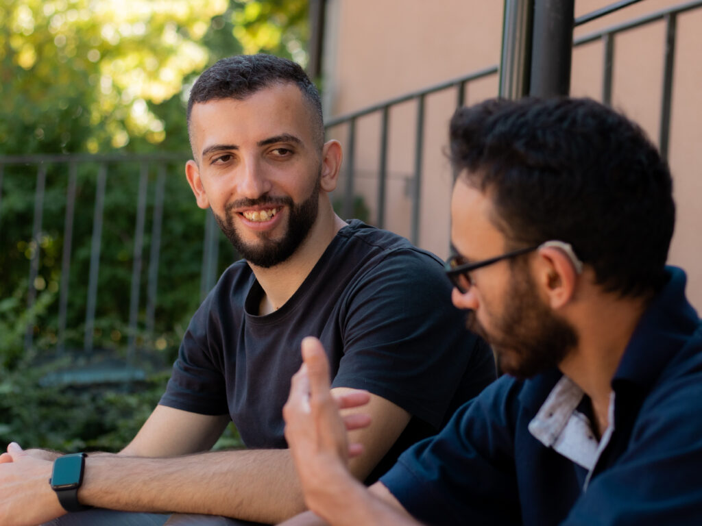 Abdulla Ahmar o Barsam Zacheri sitter på en trappa utomhus och pratar.